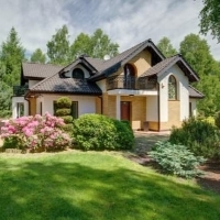 a house with a lawn and bushes in front of it