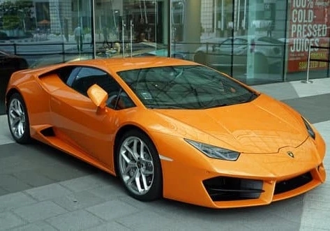 a orange sports car parked in front of a building