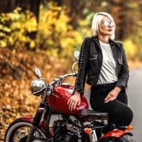 a woman sitting on a motorcycle on a road