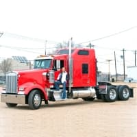 a man standing on the back of a red semi truck