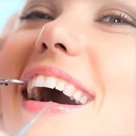 a woman getting her teeth brushed by a dentist