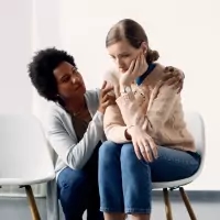 a woman sitting on a chair with her arm around a man