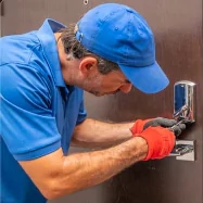 a man in blue shirt and red gloves fixing a door