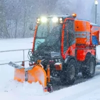 a snow plow driving down a snowy road