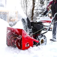 a man using a snow blower to clear snow