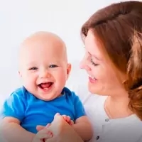 a woman holding a baby and smiling at the camera