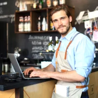 a man in an apron is using a laptop
