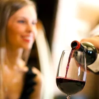 a woman pouring a glass of wine into a wine glass