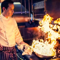 a man cooking food on a grill in a kitchen