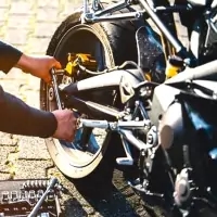 a man fixing a motorcycle tire with a wren