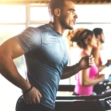 a man running on a treadmill with a woman running behind him