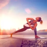 a woman doing yoga on a dock at sunset