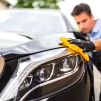 a man waxing a car with a yellow cloth