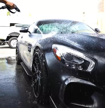 a man washing a car with a hose