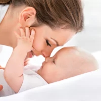 a baby being held by a woman in bed