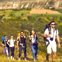 a group of people hiking up a hill with a view of a valley