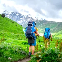two people walking in a field with backpacks