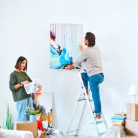 a man on a ladder painting a picture on a wall