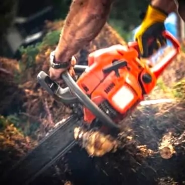 a man using a chainsaw to cut a tree