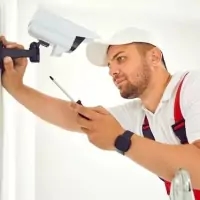 a man fixing a camera on a wall