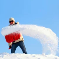 a man holding a large red object in the snow