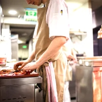 a man in a kitchen preparing food on a stove