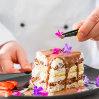 a person cutting a piece of cake on a plate