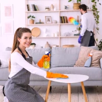 a woman cleaning a living room with a sprayer