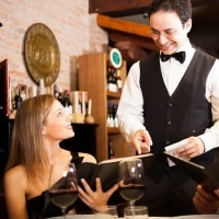 a waiter is serving a couple of people at a restaurant