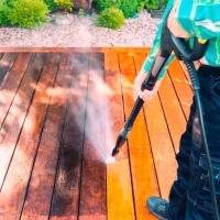 a man using a pressure gun to clean a deck
