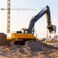 a construction site with a large excavator and a pile of gravel